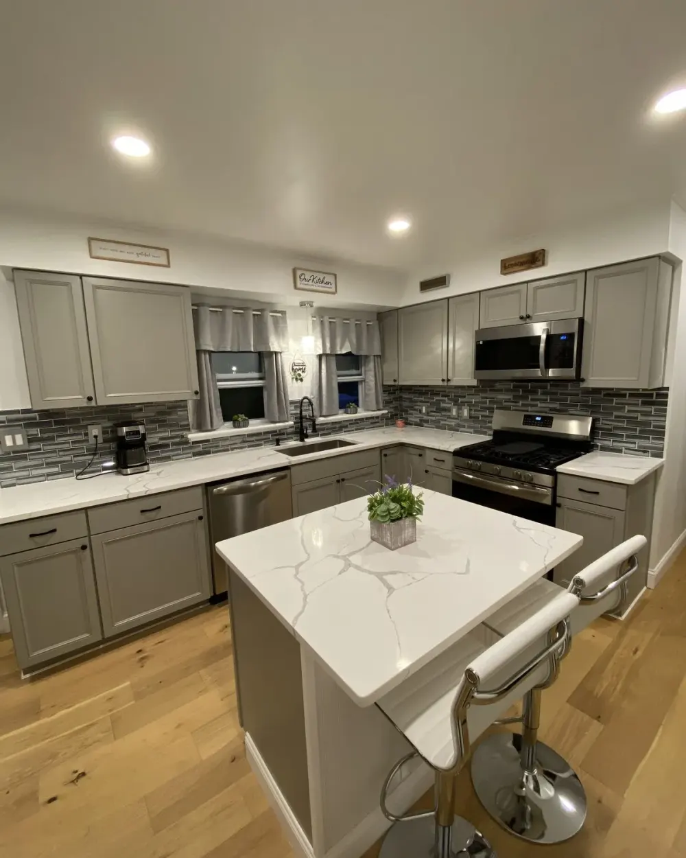 Remodeled kitchen with grey cabinetry and a quartz island, completed by Benedict's Construction